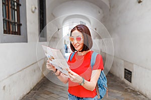 Šťastná cestovateľka sa pozerá na mapu a snaží sa nájsť správny smer k ďalšej atrakcii v európskom meste