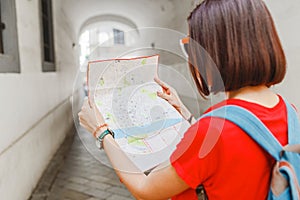 Happy girl traveler looks at the map and tries to find the right direction for the next attraction in the European city