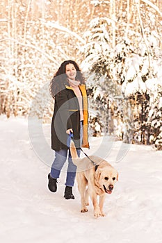 Young happy girl walks with dog labrodor in winter park
