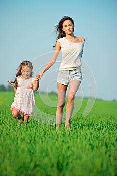 Young happy girls running at green wheat field