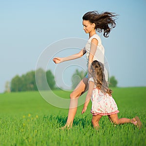 Young happy girls running at green wheat field
