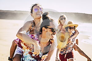 Young and happy group of cheerful smiling friends people playing together enjoying the beach in summer holiday vacation - men