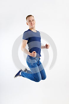 Young happy handsome man in blue shirt and jeans jumps