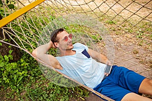 Young Happy Handsome Man Smiling In Hammock With Smartphone.