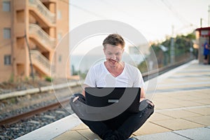 Young Happy Handsome Tourist Man Using Laptop At The Train Station