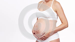 Young, happy and healthy pregnant woman in front of white background. Studio video. Baby expectation, pregnancy and