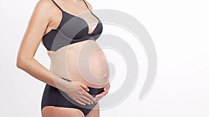 Young, happy and healthy pregnant woman in front of white background. Studio video. Baby expectation, pregnancy and