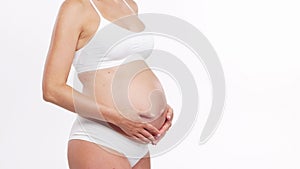 Young, happy and healthy pregnant woman in front of white background. Studio video. Baby expectation, pregnancy and