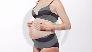 Young, happy and healthy pregnant woman in front of white background. Studio video. Baby expectation, pregnancy and