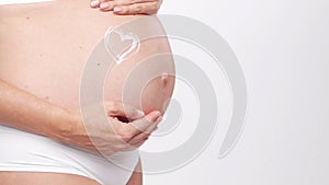 Young, happy and healthy pregnant woman in front of white background. Studio video. Baby expectation, pregnancy and