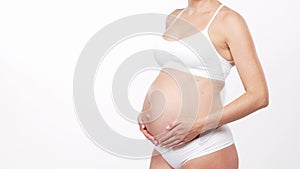 Young, happy and healthy pregnant woman in front of white background. Studio video. Baby expectation, pregnancy and