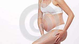 Young, happy and healthy pregnant woman in front of white background. Studio video. Baby expectation, pregnancy and