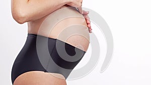 Young, happy and healthy pregnant woman in front of white background. Studio video. Baby expectation, pregnancy and