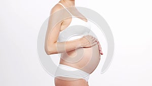 Young, happy and healthy pregnant woman in front of white background. Studio video. Baby expectation, pregnancy and