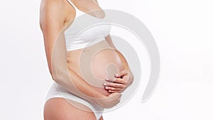 Young, happy and healthy pregnant woman in front of white background. Studio video. Baby expectation, pregnancy and