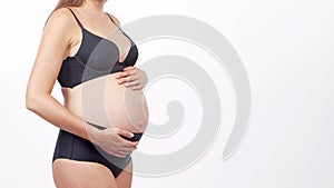 Young, happy and healthy pregnant woman in front of white background. Studio video. Baby expectation, pregnancy and