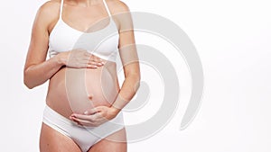 Young, happy and healthy pregnant woman in front of white background. Studio video. Baby expectation, pregnancy and