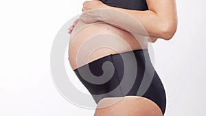 Young, happy and healthy pregnant woman in front of white background. Studio video. Baby expectation, pregnancy and