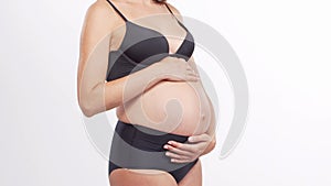 Young, happy and healthy pregnant woman in front of white background. Studio video. Baby expectation, pregnancy and