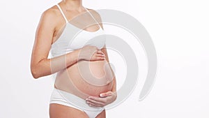 Young, happy and healthy pregnant woman in front of white background. Studio video. Baby expectation, pregnancy and