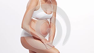 Young, happy and healthy pregnant woman in front of white background. Studio video. Baby expectation, pregnancy and