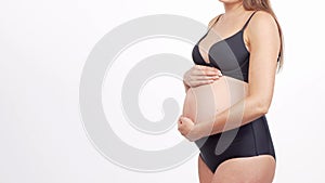 Young, happy and healthy pregnant woman in front of white background. Studio video. Baby expectation, pregnancy and