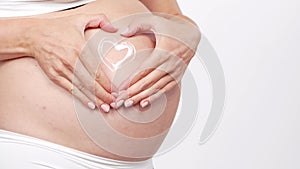 Young, happy and healthy pregnant woman in front of white background. Studio video. Baby expectation, pregnancy and