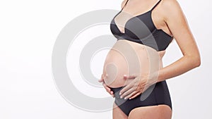 Young, happy and healthy pregnant woman in front of white background. Studio video. Baby expectation, pregnancy and