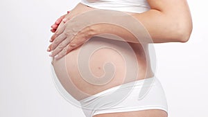 Young, happy and healthy pregnant woman in front of white background. Studio video. Baby expectation, pregnancy and