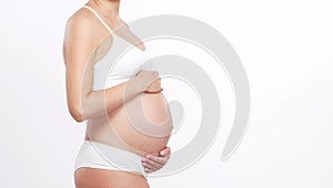 Young, happy and healthy pregnant woman in front of white background. Studio video. Baby expectation, pregnancy and