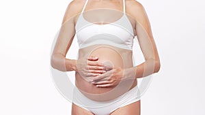 Young, happy and healthy pregnant woman in front of white background. Studio video. Baby expectation, pregnancy and