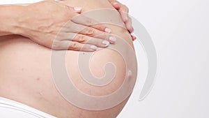 Young, happy and healthy pregnant woman in front of white background. Studio video. Baby expectation, pregnancy and