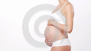 Young, happy and healthy pregnant woman in front of white background. Studio video. Baby expectation, pregnancy and