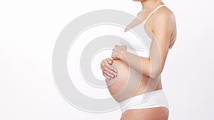 Young, happy and healthy pregnant woman in front of white background. Studio video. Baby expectation, pregnancy and