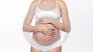 Young, happy and healthy pregnant woman in front of white background. Studio video. Baby expectation, pregnancy and