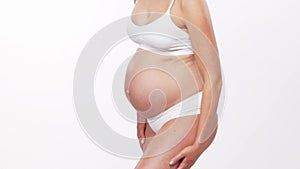 Young, happy and healthy pregnant woman in front of white background. Studio video. Baby expectation, pregnancy and