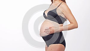 Young, happy and healthy pregnant woman in front of white background. Studio video. Baby expectation, pregnancy and