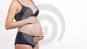 Young, happy and healthy pregnant woman in front of white background. Studio video. Baby expectation, pregnancy and