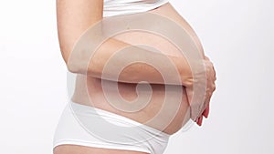 Young, happy and healthy pregnant woman in front of white background. Studio video. Baby expectation, pregnancy and