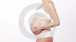 Young, happy and healthy pregnant woman in front of white background. Studio video. Baby expectation, pregnancy and