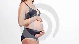 Young, happy and healthy pregnant woman in front of white background. Studio video. Baby expectation, pregnancy and