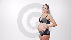 Young, happy and healthy pregnant woman on white background. Studio video. Baby expectation, pregnancy and motherhood