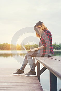 Young happy hipster woman working with her laptop sitting on pie