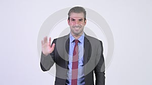 Young happy Hispanic businessman waving hand