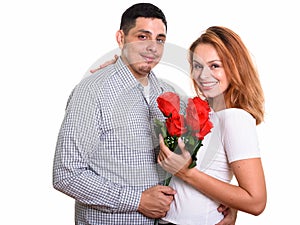 Young happy Hispanic couple smiling and in love holding red roses
