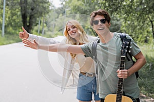 young and happy hitchhikers stopping car