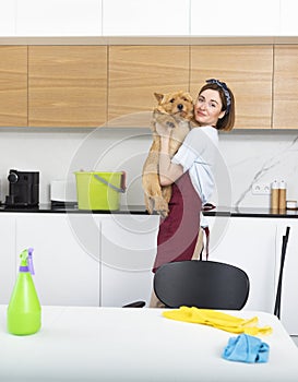 Young and happy housewife hugs her lovely pet after cleaning