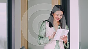 Young happy Indian business woman using tablet standing in office.