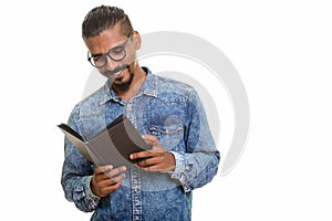 Young happy Indian man reading book studio portrait against white background