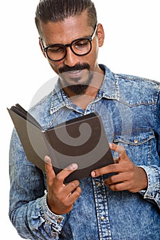 Young happy Indian man reading book studio portrait against white background